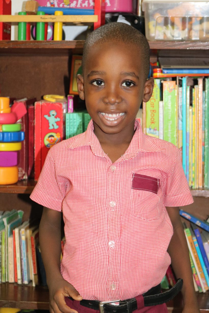 A preschool boy in a pink checked shirt in the classroom