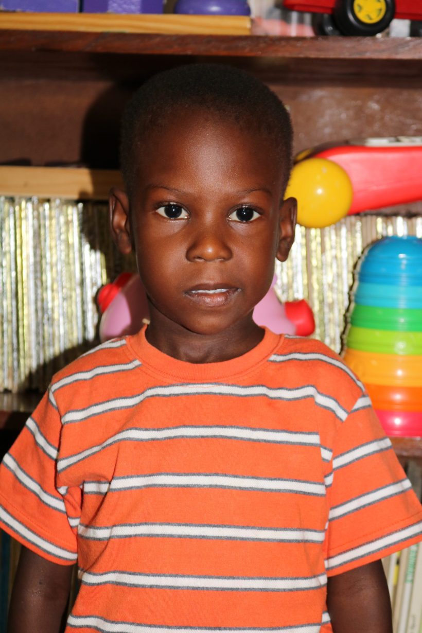 A preschool boy in an orange striped shirt in the classroom